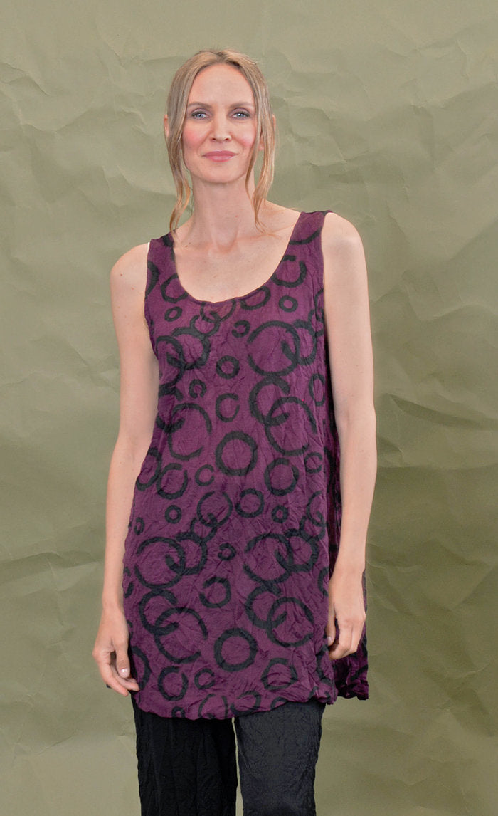 Front top half view of a woman wearing the chalet liz tank in acai. This tank is purple colored with a black circles.