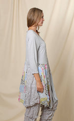 Load image into Gallery viewer, Right side top half view of a woman wearing the chalet orla jacket. The jacket in this image is grey with a mix of patchwork print and white dash print. The jacket also has 3/4 length sleeves and an asymmetrical hem.
