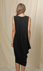 Load image into Gallery viewer, Back full body view of a woman wearing the chalet romaine dress. This dress is black and sleeveless. The right side has a draping effect and the dress sits slightly below the knees.
