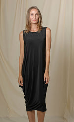 Load image into Gallery viewer, Front full body view of a woman wearing the chalet romaine dress. This dress is black and sleeveless. The right side has a draping effect and the dress sits slightly below the knees.
