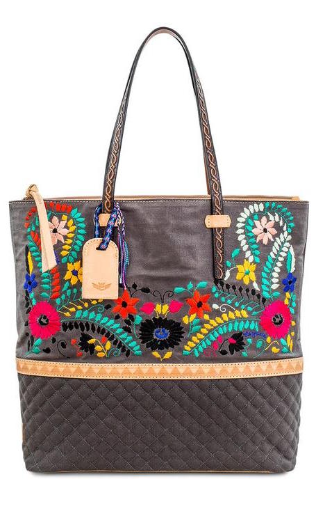 Front view of the consuela silverlake market tote. This tote is grey with a quilted like bottom and light tan trim. The straps are thin. On the front of the tote is blue pink and orange floral embroidery.