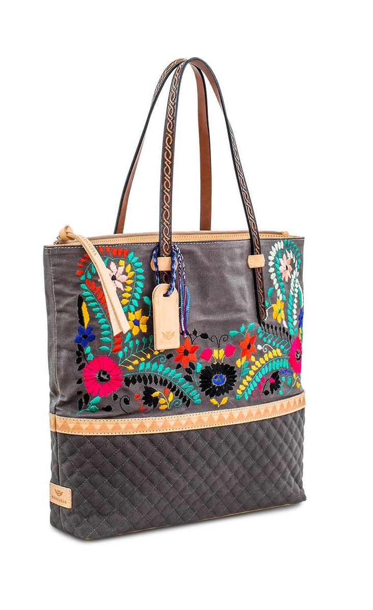 Front right side view of the consuela silverlake market tote. This tote is grey with a quilted like bottom and light tan trim. The straps are thin. On the front of the tote is blue pink and orange floral embroidery.