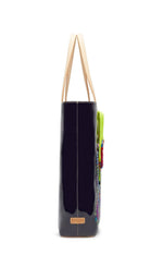 Load image into Gallery viewer, Right side view of the consuela tia slim tote. This tote is a glossy black with a thin tan leather strap and colorful embroidery on the front.
