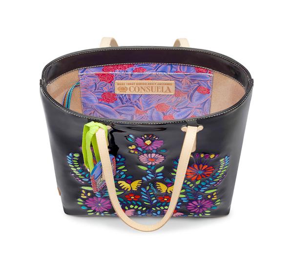 Inner view of the consuela tia slim tote. This tote is a glossy black with a thin tan leather strap and colorful embroidery on the front. The inside has a slide pocket.