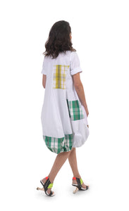 Back full body view of a woman wearing the alembika plaid wonderful dress. This dress is white with yellow, green, and brown plaid panelling/patches. The dress has short sleeves. The bottom is wide and full.