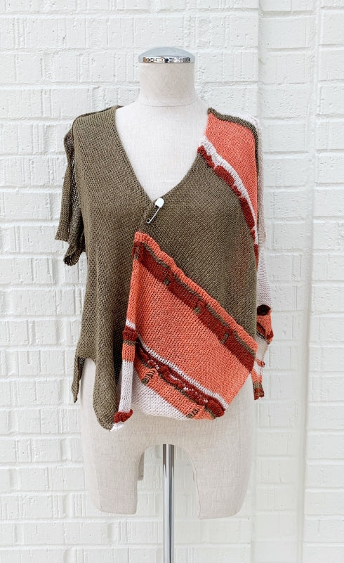 Front view of the crea concept asymmetrical knit top. This top is brown on the right side with a short sleeve and salmon and brown striped on the left side with a sleeveless, draped look. Both sides come together in the middle of the front with a safety pin.