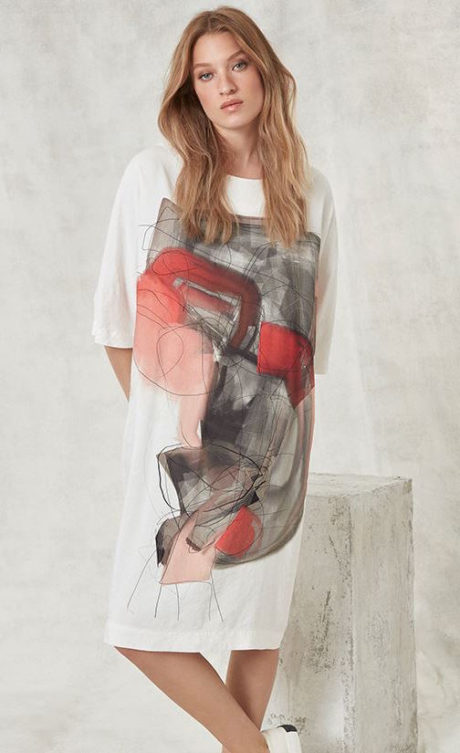 Front full body view of a woman wearing the Crea Concept Abstract T-Shirt Dress. This dress is white with 3/4 length sleeves, a round neck, and an abstract grey/orange print in the front.