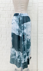 Load image into Gallery viewer, Back view of the crea concept abstract watercolor pant. This pant is wide legged and has a teal watercolor-like print on it. 
