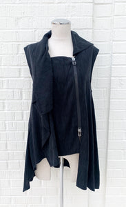 Front view of the crea concept black vest/top. This top is sleeveless with a draped front, a zipper on the front left side, and an asymmetrical hem.