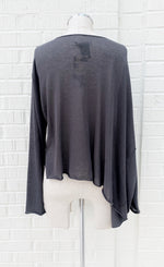 Load image into Gallery viewer, Back view of the crea concept knit cape top. This top is grey and semi-translucent. It has long sleeves and a cape like feature on the right side.
