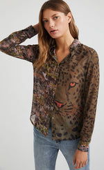 Load image into Gallery viewer, Front top half view of a woman wearing the desigual daytona wild print shirt. The base color of this shirt is green/brown. It has an animal print with a tiger face on the left side and a mixed watercolor print on the right side. The shirt has a button up front and long sleeves with cuffs.

