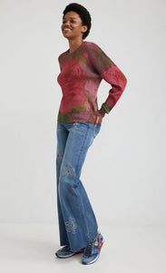 front full body view of a woman wearing the desigual knit flowers sweater. This sweater is ribbed with large pink roses printed all over it. It has long sleeves and a loose fit.