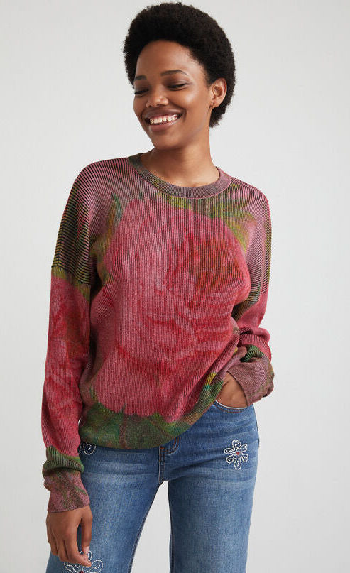 front top half view of a woman wearing the desigual knit flowers sweater. This sweater is ribbed with large pink roses printed all over it. It has long sleeves and a loose fit.