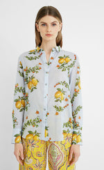 Load image into Gallery viewer, Front top half view of a woman wearing yellow paisley capris and the desigual lemons cotton shirt. This shirt is blue with lemons printed on it. The top has a button down front, a shirt collar, and long sleeves.
