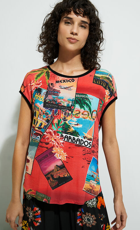 Front top half view of a woman wearing the desigual postcards short sleeve t-shirt. This top is red with tropical post cards all over it and flowers. The top has short sleeves, a round neck, and a rounded hem.