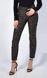 Front bottom half view of a woman wearing the frank lyman reversible zebra/black pant. This side of the pant is brown and black zebra print. The pants are slim fitting.
