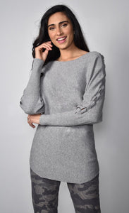 Front top half view of a woman wearing the frank lyman grey knit sweater. This solid sweater has long sleeves with a braided detail running down the sides.