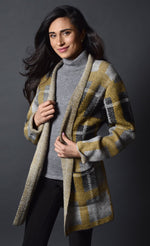 Load image into Gallery viewer, Front top half view of a woman wearing the frank lyman plaid sweater jacket. This jacket is open over a grey turtleneck and the model is wearing it with black sweatpants. The grey and mustard jacket has long sleeves and two front patch pockets.
