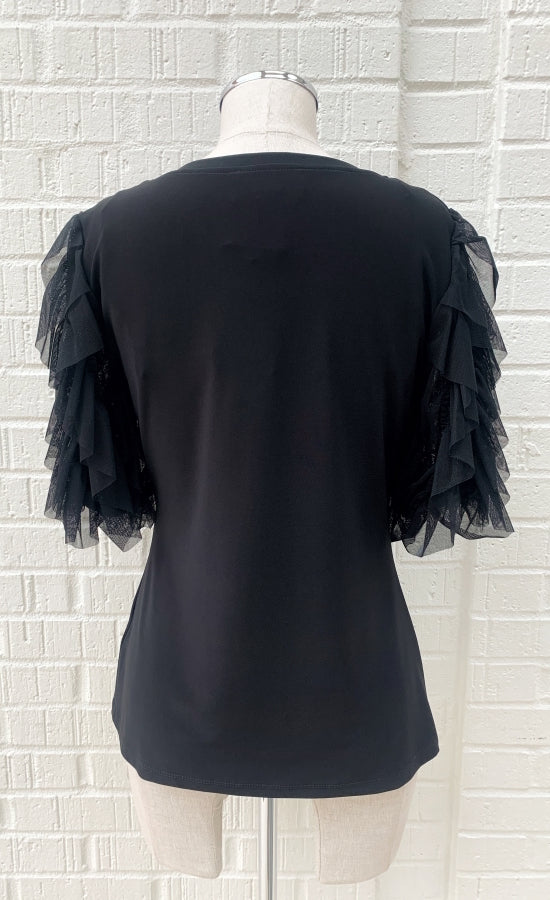 Back view of a mannequin wearing a black jersey knit top with sheer sleeves from Frank Lyman. The sheer sleeves are ruffled and 3/4 length.