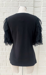 Load image into Gallery viewer, Back view of a mannequin wearing a black jersey knit top with sheer sleeves from Frank Lyman. The sheer sleeves are ruffled and 3/4 length.
