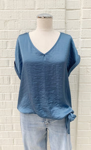 Front view of a mannequin in a light blue stain top from Frank Lyman with short, folded over sleeves and a side tie