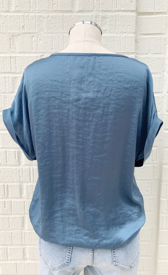 Back view of a mannequin in a light blue stain top from Frank Lyman with short, folded over sleeves and a side tie