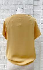 Load image into Gallery viewer, Front view of a mannequin wearing a marigold woven top from Frank Lyman with short sleeves.
