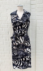 Load image into Gallery viewer, Front view of a mannequin wearing the Frank Lyman Wild Thing Dress. This dress features a navy, beige, and white animal print and zebra print mixed fabric, a tie belt at the waist, and a flat, notched collar with an off-center zipper.
