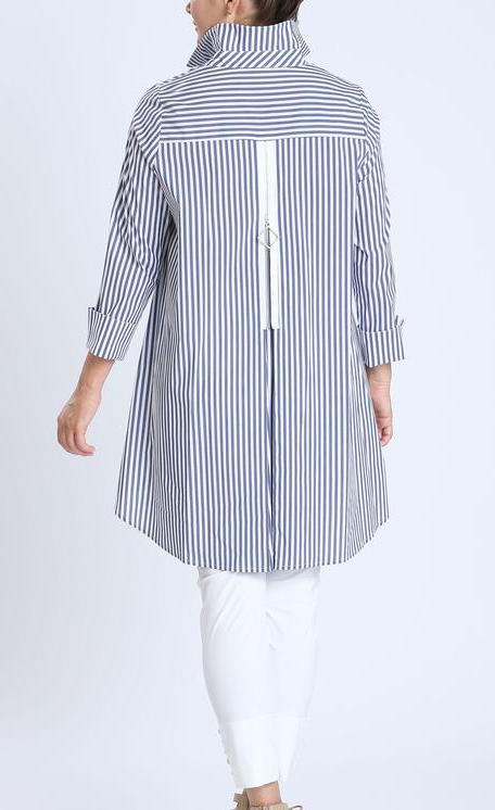 Back top half view of a woman wearing white pants and the IC Collection Navy Striped Shirt. This shirt has vertical navy and white stripes in the back and on the arms with diagonal stripes on the side and horizontal stripes on the shoulder. The shirt has cuffed 3/4 length sleeves and a centered zipper in the back.