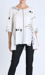 Load image into Gallery viewer, Front top half view of a woman wearing black pants and the IC Collection white scribble top. This white top has black scribbles and ink spots all over it. The top also has a rounded neck, a flowy silhouette, and 3/4 length sleeves.

