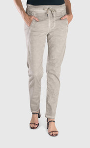 Front bottom half view of a woman wearing the alembika grey iconic stretch jeans. This light grey jeans have a drawstring waistband with a tie, two front pockets and a relaxed slim/straight cut.