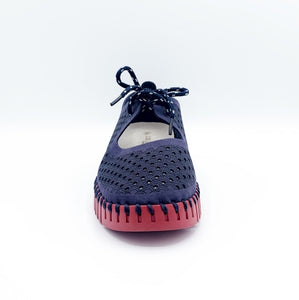 Front view of the ilse jacobsen tie flat. This flat is navy with a red sole. The upper has a scale like pattern with perforated tiny holes all over it. The shoe has a lace up front.