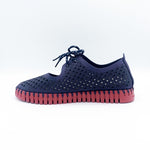 Load image into Gallery viewer, Inner side view of the ilse jacobsen tie flat. This flat is navy with a red sole. The upper has a scale like pattern with perforated tiny holes all over it. The shoe has a lace up front.
