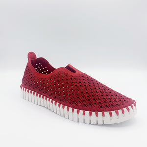 Front, outer view of the ilse jacobsen tulip flat in deep red. This flat shoe has a white sole and a scale-like red upper. The upper is perforated with tiny holes all over it.