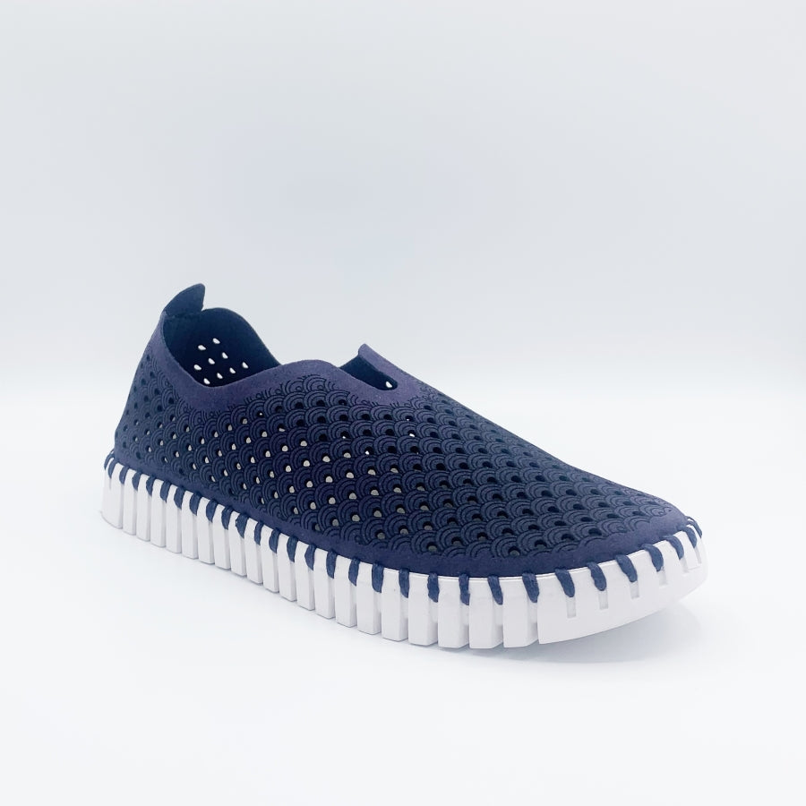 Front, outer view of the ilse jacobsen tulip flat in navy. This flat shoe has a white sole and a scale-like navy upper. The upper is perforated with tiny holes all over it.