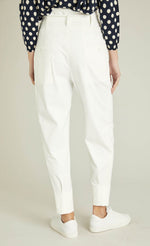 Load image into Gallery viewer, Back bottom half view of a woman wearing a blue and white polka dot top and the indies white collin pants. These pants have a carrot shape, two back patch pockets, and a tie belt.
