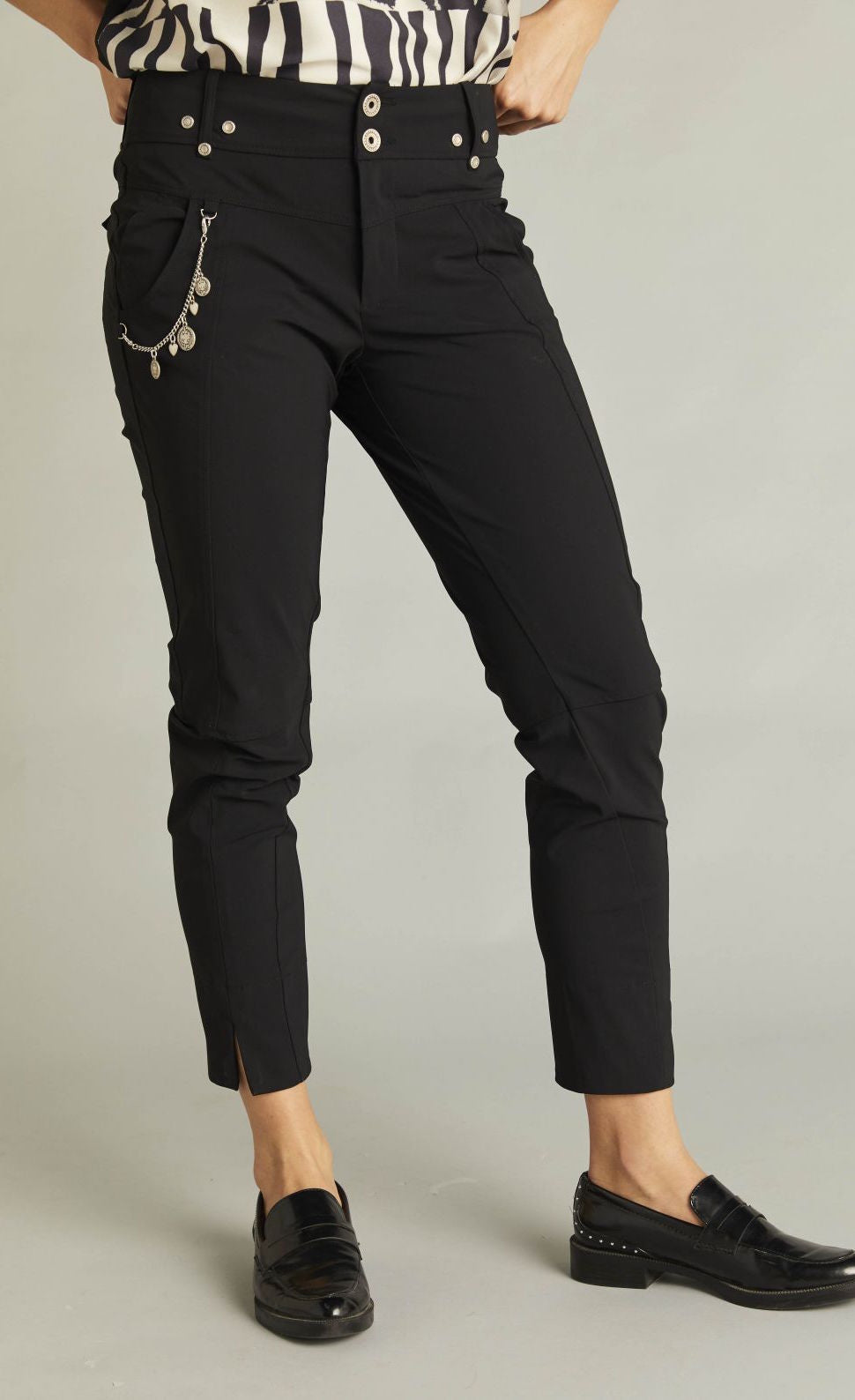 Front bottom half view of a woman wearing a black top and the black indies epatant pants. These pants have two front patch pockets and a side chain on the right side. The pants are slightly cropped and sit above the ankles.