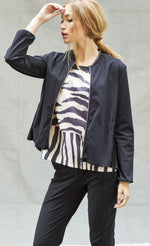 Load image into Gallery viewer, Front top half view of a woman wearing black pants, and black and white tank with the indies black fute jacket over it. This jacket has a zip front, long sleeves, and a short collar.

