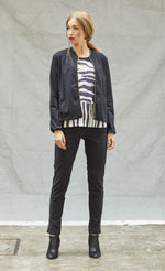Load image into Gallery viewer, Front full body view of a woman wearing black pants, and black and white tank with the indies black fute jacket over it. This jacket has a zip front, long sleeves, and a short collar.
