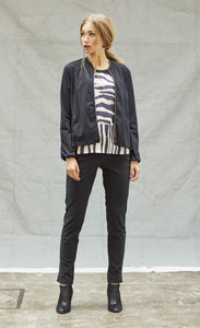 Front full body view of a woman wearing black pants, and black and white tank with the indies black fute jacket over it. This jacket has a zip front, long sleeves, and a short collar.