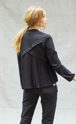Load image into Gallery viewer, Back top half view of a woman wearing black pants and the indies black fute jacket. This jacket has pleats on the back with a criss-crossing of fabric on the upper back.
