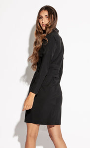 Back full body view of a woman looking behind herself and wearing the Indies Irina Dress. This black fitted dress cuts off above the knees and has long sleeves and a large tie belt on the waist.