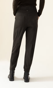 Back bottom half view of a woman wearing the indies luna kaki pant. These pants have a large waistband with a tie belt, back patch pockets, a relaxed fit, and a tapered elastic hem.