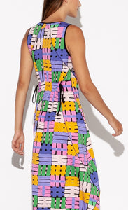 Back top half view of a woman wearing the Indies Nils Dress. This dress has multicolored hashtags printed all over it. It is sleeveless and the back of the neck and armholes are lined with black. The back features two adjustable ties at the waist to cinch it in.
