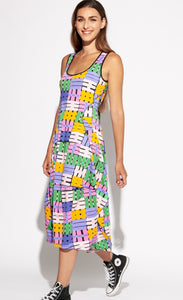 Front full body view of a woman wearing the Indies Nils Dress. This dress has multicolored hashtags printed all over it. It is sleeveless with a round neckline that is lined with black trim. The dress sits below the knees but above the ankles.