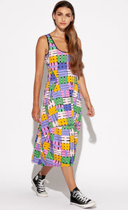 Front full body view of a woman wearing the Indies Nils Dress. This dress has multicolored hashtags printed all over it. It is sleeveless with a round neckline that is lined with black trim. The dress sits below the knees but above the ankles.