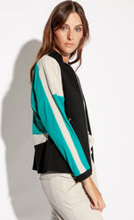 Load image into Gallery viewer, Ride side top half view of a woman wearing pebble colored Indies collin pants and the Indies Nano Jacket. The jacket has a black front, a seafoam blue sleeve, and beige/pebble colored, perforated sleeves. 
