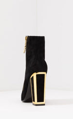 Load image into Gallery viewer, Back view of the black kat maconie anges boot. This boot has a high heel and the heel is framed with gold. The outer side has a gold zipper with a star pull tab.
