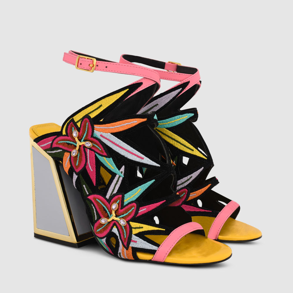 Outer side view of a pair of the calypso kicker heel sandals from kat maconie. These open toe sandals have a tall framed heel, an ankle strap and embroidered, multicolored birds of paradise flowers covering the  sides of the foot.