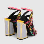 Load image into Gallery viewer, back side view of a pair of the calypso kicker heel sandals from kat maconie. These open toe sandals have a tall framed heel, an ankle strap and embroidered, multicolored birds of paradise flowers covering the  sides of the foot.
